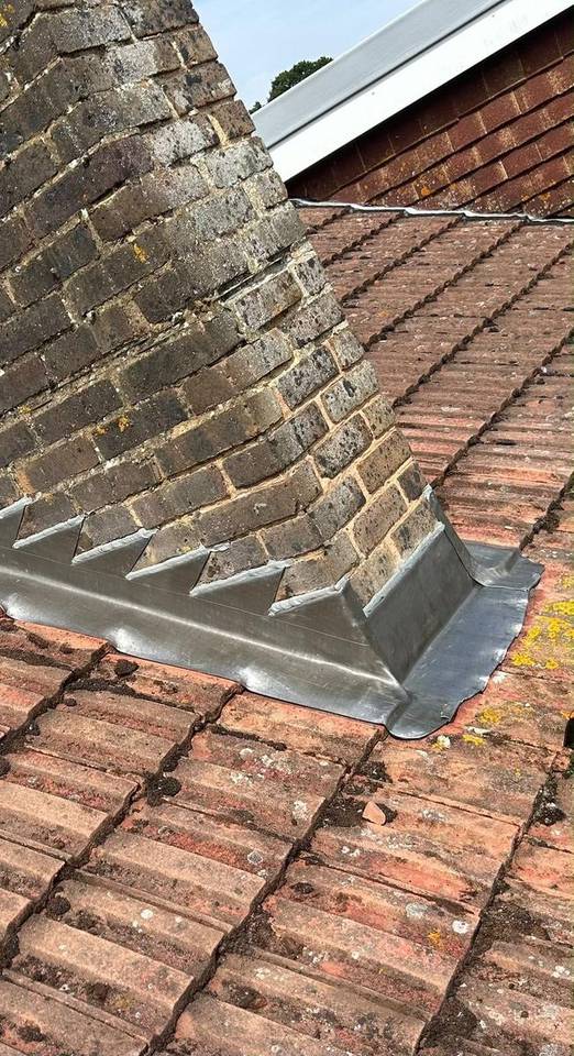 Brick chimney stack with stepped lead flashing on a clay tile roof