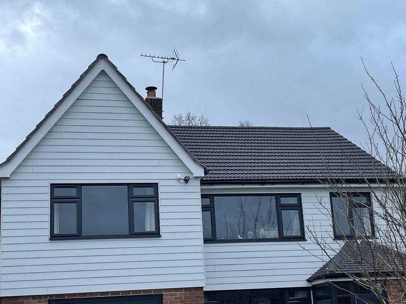 Front of a house with a grey tiled roof, white weatherboarded gable and white fascias