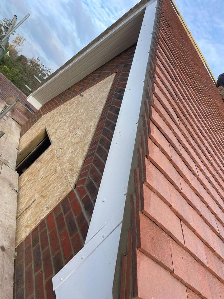 White UPVC bargeboard and verge detail against a clay tile roof and brick dormer cheek