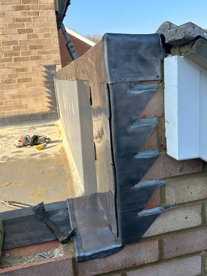 Lead flashing dressed around a brick wall abutment on a flat roof