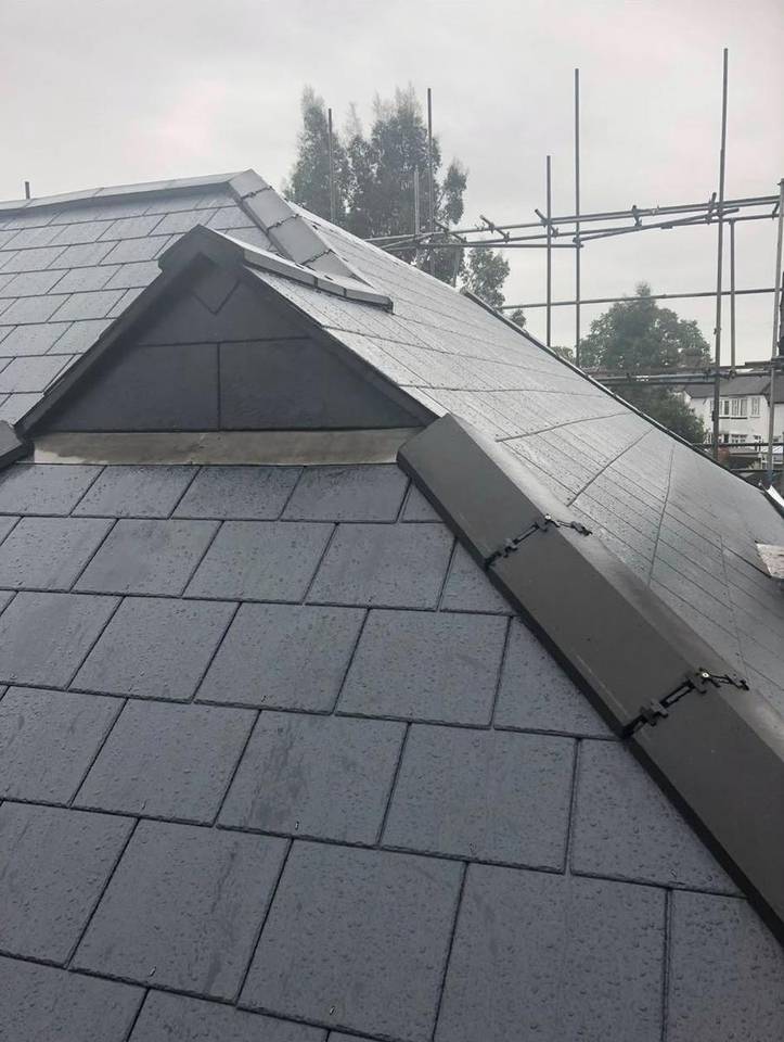 Grey slate roof with a small dormer and ridge detail, scaffold behind